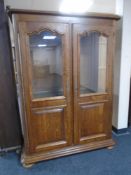 A continental oak double door display cabinet on bun feet.