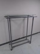 A twin sided portable metal clothes rail with glass shelf.