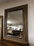 A contemporary bevel edged mirror in green and gilt frame.