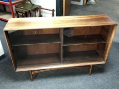 A mid-20th century teak sliding door bookcase on raised legs.