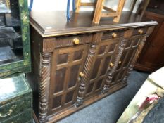 A continental stained pine triple door sideboard fitted with three drawers above with twist column