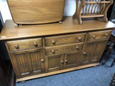 An Ercol elm and beech Canterbury sideboard on bun feet.