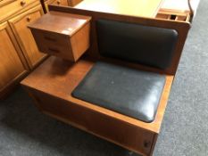 A mid-20th century teak telephone table with black vinyl seat.