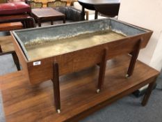 A mid century Danish teak plant trough with metal liner raised on castors,