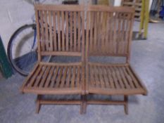 A pair of folding teak garden chairs.