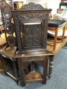 A 19th century carved oak corner cabinet on table.