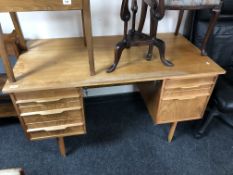 A mid-20th century teak twin pedestal desk on raised legs, with keys.