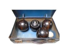 A vintage case containing four wooden lawn bowls