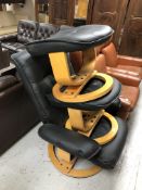 A black vinyl upholstered swivel armchair with two stools