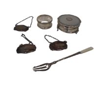 A silver napkin ring together with three silver decanter labels,