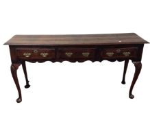 A George III mahogany and oak dresser base fitted with three drawers on pad feet.