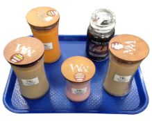 A Yankee candle together with four Woodwick candles.