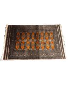 A Lahore Bokhara rug, Pakistan, with repeated terracotta 'gul' motif on mauve ground,