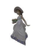 A Lladro figure of a child holding a basket of flowers.
