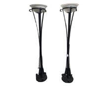 A pair of contemporary metal uplighters with glass shades