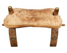 A camel stool with leather cushion.