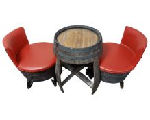 A barrel table together with a pair of wood and red vinyl chairs.