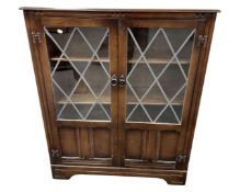 An oak linenfold bookcase with leaded glass doors.