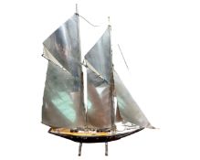 A wood and chrome model of a sailboat.