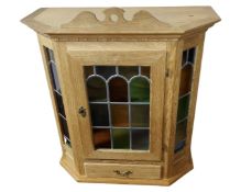 A Continental blond oak wall cabinet with stained leaded glass panels.