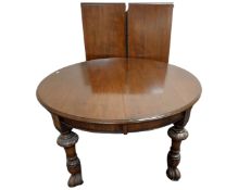 A 19th century oval wind out dining table with two leaves on carved legs