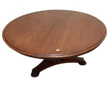 A circular mahogany coffee table on triform base,