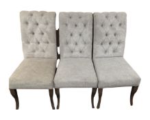 A set of three contemporary high backed dining chairs in grey buttoned fabric with metal