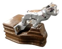 A Mack Truck bulldog bonnet mascot mounted on a wooden plinth.