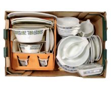 A box containing vintage Pyrex dishes, tea and dinnerware.