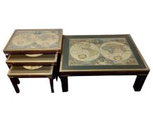 A brass bound glass top coffee table depicting a map of the world together with a similar nest of