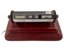 Two 20th century metal scroll calendars, one mounted on leather plinth.