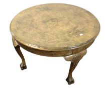 A circular walnut coffee table on paw feet.