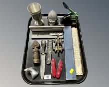 A tray containing a desk punch, pocket knives, a Unique slide rule,