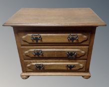 A continental oak three drawer chest on bun feet.