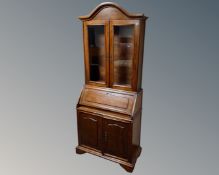 A fall front bureau-bookcase fitted with cupboards beneath.