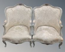 A pair of French Louis XV style cream and gilt armchairs.