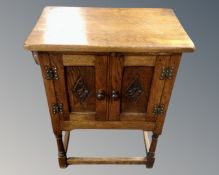 A carved oak double door cabinet on raised legs.