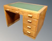 A mid-20th century oak single pedestal desk fitted with a green leather inset panel and five