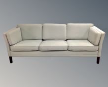 A 1970s Danish three seater settee upholstered in green fabric.