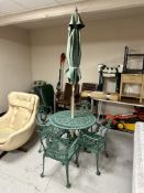 A circular cast metal patio table and four armchairs with parasol