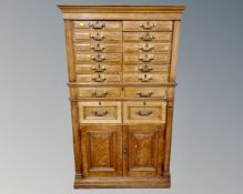 A late Victorian oak sixteen-drawer filing chest fitted with brass drop handles and cupboards