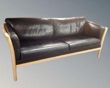 A Scandinavian wood framed settee with black leather cushions.