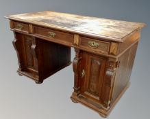 An antique oak twin pedestal writing desk fitted with cupboards and drawers (width 134cm),