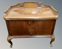 An antique mahogany double door serving cabinet on raised legs with gallery.