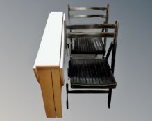 A drop leaf kitchen table together with two folding chairs.