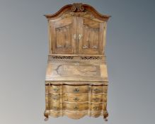 A 19th century oak serpentine fronted secretaire bureau fitted with three drawers below and