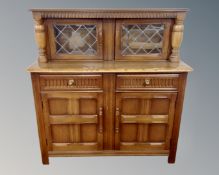 An Ercol solid elm and beech double door buffet back sideboard in an oak finish.