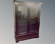 A stained hardwood double door glazed bookcase fitted with drawers below.