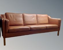 A Hurup three seater settee with tan leather cushions.