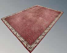 An Iranian carpet with repeat boteh motif on red ground, 270cm by 366cm.